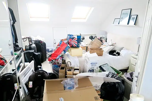 Vollgestelltes Dachgeschosszimmer mit Kartons, Koffern und Säcken vor der Wohnungsentrümpelung